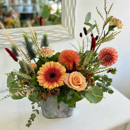 Low orange and peach flower arrangement with gerbera daisy, dahlias, and roses in a gray rectangular vase
