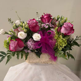 Pink and white rose bouquet in a textured box with a purple ribbon