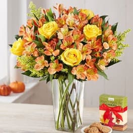 Yellow roses and orange alstroemeria in a clear glass vase