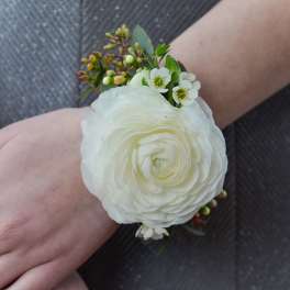 White flower wrist corsage with small green accents