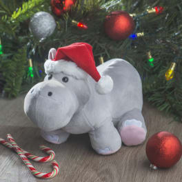Plush hippo wearing a Santa hat beside a Christmas tree with ornaments and candy canes