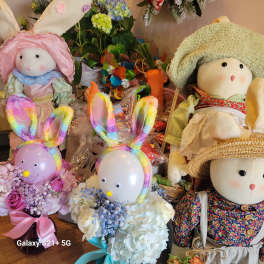 Plush bunny dolls with colorful bunny-ear balloons and flower bouquets