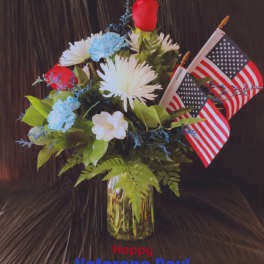 Bouquet of red, white, and blue flowers in a glass vase with two small American flags