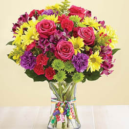 Colorful mixed bouquet of roses, daisies, and carnations in a clear vase