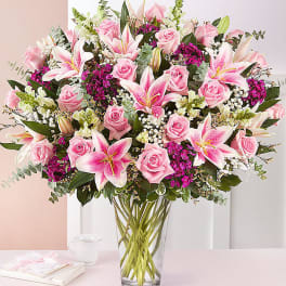 Pink roses and lilies arranged in a clear glass vase