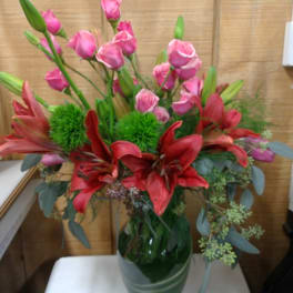 Pink roses and red lilies arranged in a glass vase