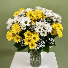 Yellow and white daisy bouquet in a clear glass vase