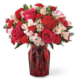 Red and pink flower bouquet in a red glass vase