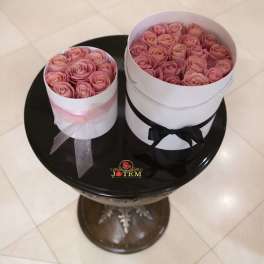Two round boxes filled with pink roses and ribbon bows