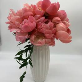 Pink peony bouquet in a tall white vase