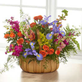 Mixed bouquet of orange, purple, and pink flowers in a pumpkin-shaped container