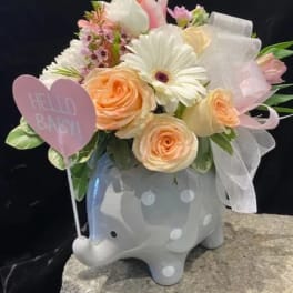 Pastel flower arrangement in a gray elephant planter with a pink heart sign