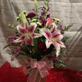 Pink and white lily bouquet in a vase with a pink ribbon