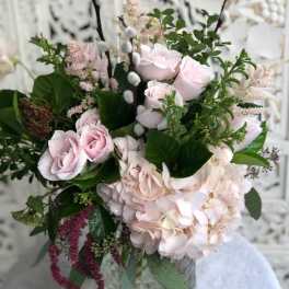 Pink roses and hydrangea in a glass vase with greenery