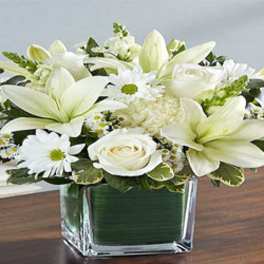 White lilies and roses in a square glass vase