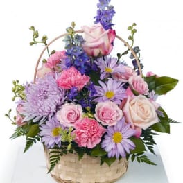 Pastel pink and lavender mixed flower basket with roses, carnations, daisies, and delphinium