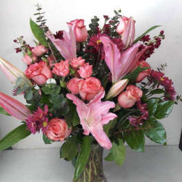 Pink roses and lilies arranged in a clear glass vase