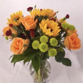 Bouquet of orange roses and yellow sunflowers in a glass vase