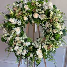 Large floral wreath on a wooden easel with white and green blooms