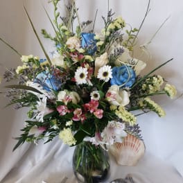 Mixed bouquet in a glass vase with blue, white, and pink flowers
