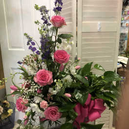 Tall bouquet of pink roses, purple flowers, and white blooms with a pink ribbon