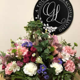 Mixed pink, white, and purple flowers in a wicker basket arrangement