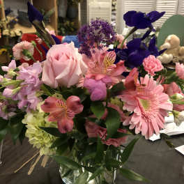 Mixed bouquet with pink roses, gerbera daisies, and purple blooms in a glass vase
