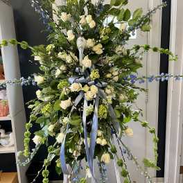 Large standing floral spray with white roses and blue accents on an easel