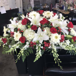 Large floral casket spray with white lilies, red roses, and white daisies