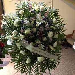 Large funeral spray of white lilies and mixed flowers with a ribbon