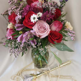 Mixed bouquet of roses, daisies, and purple blooms in a glass vase
