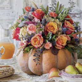 Floral arrangement in a pumpkin centerpiece with pears nearby