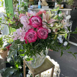 Pink roses and lilies arranged in a clear glass vase