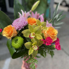 Handheld bouquet with orange roses, pink lilies, and green orchids