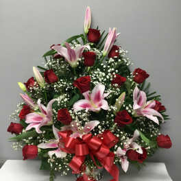 Red roses and pink lilies arranged with baby's breath and a red ribbon