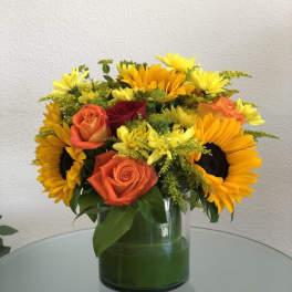 Bouquet of orange roses and yellow sunflowers in a glass vase