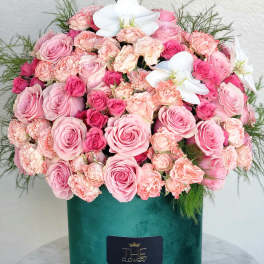 Pink roses and carnations in a green velvet box with white orchids