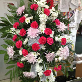 Standing floral spray with pink and white flowers on a black easel
