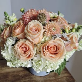 Peach roses and white hydrangeas in a low round vase arrangement