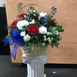 Basket arrangement of red, white, and blue carnations on a pedestal