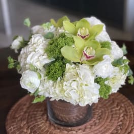 White floral arrangement with green orchids in a vase