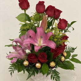 Red roses and pink lilies in a white basket with gold chocolates