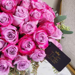 Bouquet of pink roses in a glass vase with a black tag