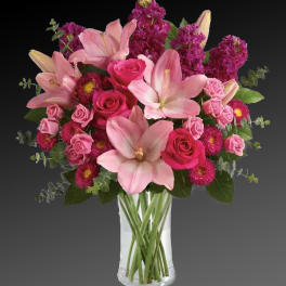Pink lilies and roses arranged in a clear glass vase