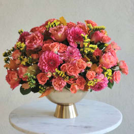 Pink and coral flower arrangement in a gold pedestal vase
