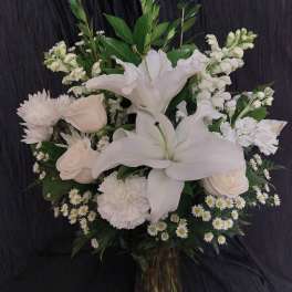 White lilies and roses arranged in a tall vase with greenery