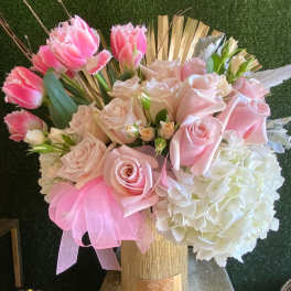 Pink roses, fringe tulips, and white hydrangeas in a gold vase with a pink bow