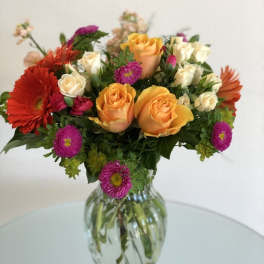 Mixed bouquet of roses and daisies in a clear glass vase