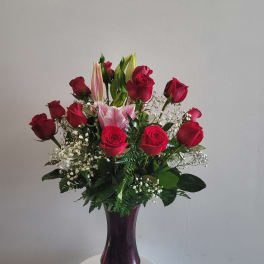Red roses and pink lilies in a purple glass vase