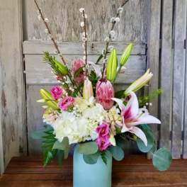 Pink lilies and roses in a blue vase with white hydrangeas